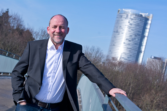 Dirk Kleine seit über 25 JAhren Immobilienmakler in Bonn, vor Posttower auf einer Brücke